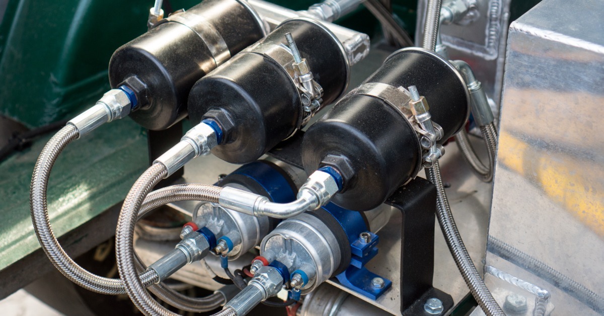 Close-up of a nitrous oxide system in a car trunk. It features five canisters that connect to each other with metal tubes.